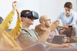 © Maya Claussen/Westend61 - Happy family sitting on couch, using VR goggles and mobile devices