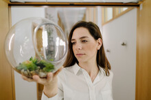 Businesswoman Holding Terrarium In Hand While Standing At Office
