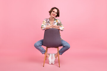 Wall Mural - Full length body size photo woman sitting on chair wearing stylish outfit isolated pastel pink color background