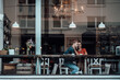 © Joseffson/Westend61 - Young woman with arm around on man sitting by cafe window