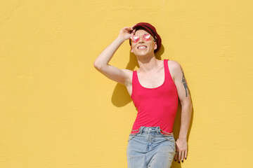 Wall Mural - Young non-binary model smiling while posing outdoors leaning against a yellow wall.