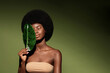 Natural organic cosmetics concept.  Beauty portrait of young beautiful african american woman with posing with banana leaf curly hair against green exotixc plants background.