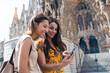 © JOSEP SURIA/Westend61 - Smiling friends using mobile phone while standing against Sagrada Familia at Barcelona, Catalonia, Spain