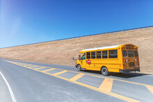 Yellow School Bus On Highway Against Clear Blue Sky