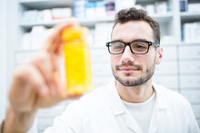 Smiling Pharmacist Holding Pill Box In Pharmacy