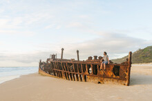 Man Sitting On Maheno Shipwreck At Fraser Island, Queensland, Australia