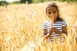 © Pavel Horak/Westend61 - Little girl standing in wheat field, looking at wheat ear
