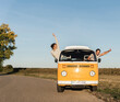 © UWE_UMSTAETTER/Westend61 - happy couple waving and cheering out of their camper, having fun on their road trip