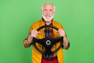 Poster - Photo of good mood funny senior gentleman wear yellow vest driving car smiling isolated green color background