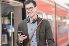 Smiling Young Man With Cell Phone At Commuter Train