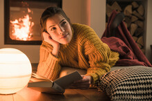 Young Woman Reading Book At The Fireplace At Home