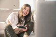 © UWE_UMSTAETTER/Westend61 - Happy young woman playing video game at home