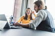 © UWE_UMSTAETTER/Westend61 - Young businesswoman and businessman sitting at desk in office talking