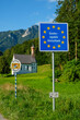 © Lisa Bahnm√ºller/Westend61 - Germany, Bavaria, Nussdorf, State border information sign with Kreuzkirche in background