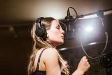 Singer With Headphones At Microphone In Recording Studio