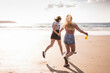 © UWE_UMSTAETTER/Westend61 - Two girlfriends having fun, running and jumping on the beach