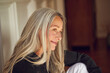 © Maya Claussen/Westend61 - Smiling mature woman sitting at home
