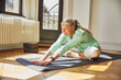 © Maya Claussen/Westend61 - Woman exercising while sitting on exercise mat over floor in living room