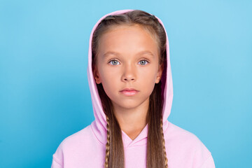 Photo of serious young charming small girl wear hood sweatshirt face isolated on blue color background