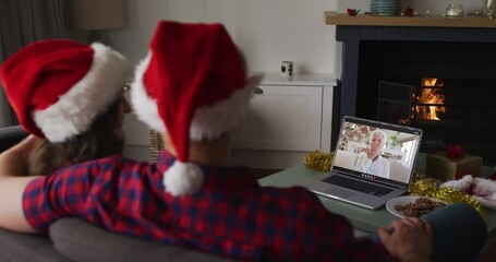 Canvas Print - Caucasian couple on video call on laptop with grandmother at christmas time