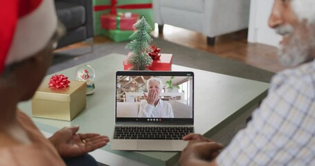 Canvas Print - Happy senior african american couple on video call on laptop with female friend at christmas time