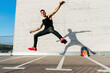 © MANU RUIZ PHOTOGRAPHY/Westend61 - Young man with arms outstretched jumping on footpath during sunny day