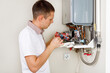 © Ruslan Ivantsov - Plumber attaches Trying To Fix the Problem with the Residential Heating Equipment. Repair of a gas boiler