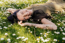 Happy Woman Enjoying Her Free Time While Lying On Grass With Daisies