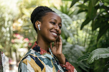 Happy Young Woman Listening Music With Earphones In Garden
