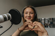 © Mareen Fischinger/Westend61 - Close-up of smiling teenage girl making heart shape while singing in recording studio