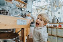 Excited Little Boy Pointing At Chocolate Jar In Candy Shop
