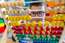 Boy Calculating With Colorful Abacus At Home