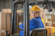 © Westend61 - Smiling woman wearing hard hat driving forklift in factory