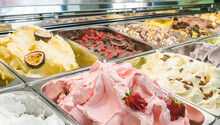 Multi Colored Italian Ice Cream Gelato With Various Fruit Flavors Decorated With Fruits, Nuts Or Chocolate  In The Refrigerator-display Case. Ice Cream Trays.
Italian Cuisine. Gourmet Dessert.
