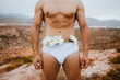 © Westend61 - Man wearing underwear with flowers in field during sunset