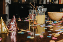 Close-up Of Drinks With Party Hats And Confetti On Dining Table At Home