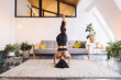 © Mareen Fischinger/Westend61 - Woman practicing Sirsasana in living room at home