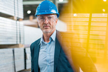 Portrait Of Mature Businessman Wearing Hard Hat And Safety Goggles In A Factory