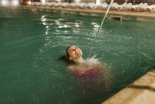 Water Splashing On Cheerful Woman Swimming In Thermal Pool At Night