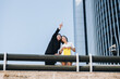 © Manu Reyes,www.vientocuatro.com/Westend61 - Smiling businesswoman pointing female coworker at downtown district in city against clear sky