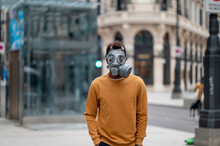 Man Wearing Protective Gas Mask Standing With Hands In Pockets At City