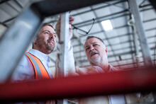 Businessman And Man In Reflective Vest Talking In Industrial Hall