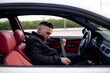 © Oscar Carrascosa Martinez/Westend61 - Young man wearing jacket adjusting seat belt while sitting in car