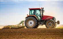 Farmer In Tractor Plowing Field In Spring