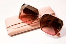 Pink women's glasses and leather case on a white background