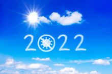Happy New Year Concept. Bright Sun, Number 2022 And A Crossed Out Corona Virus On Blue Sky, Symbolizing An End To The Covid-19 Pandemic.
