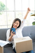 Happy young Asian woman entrepreneur, Smile for sales success after checking order from online shopping store in a smartphone at home office, Concept of merchant business online and eCommerce