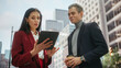 © Gorodenkoff - Confident Businesswoman Showing Financial Projections to Her Work Partner on Laptop Computer. Manager and Entrepreneur Discussing a Project Outside on a Street in Big City in Downtown.