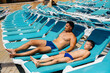 © Andrii - A young athletic man and his son are smiling happily and sunbathing on a sun lounger on a sunny day. Happy vacation vacation. Summer holidays and tourism.