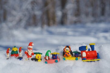 Wall Mural - Toy train with fairy-tale characters and gifts in the winter forest. Gnome, Santa Claus, penguin and snowman.